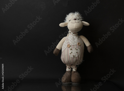 samotna owieczka maskotka na czarny tle z delikatnym odbiciem