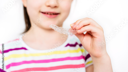 Little girl is holding invisible aligner orthodontic and braces. Close-up, banner, copy space