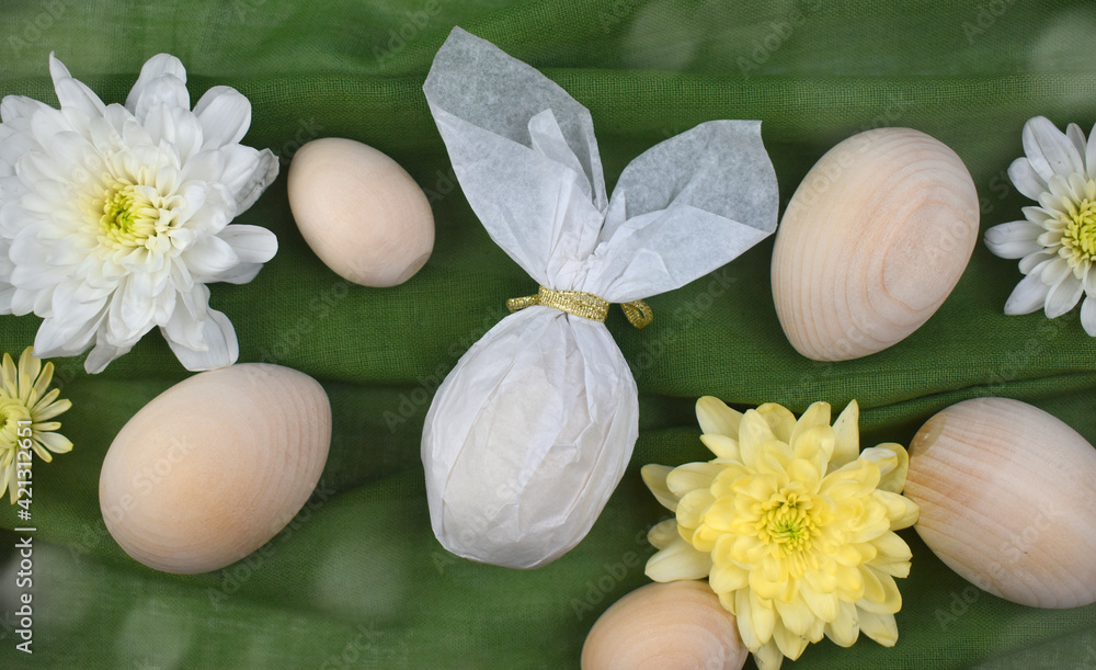 Easter holiday composition with wooden eggs, bunny egg and flowers on green fabric. Handmade creative concept. Eco friendly style.