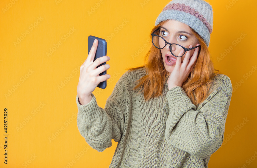 Scared young woman with mobile phone, isolated on yellow background. Shocked female person holding smartphone. Unbelievable Scared young woman with mobile phone, isolated on yellow background. Shocked female person holding smartphone. Unbelievable