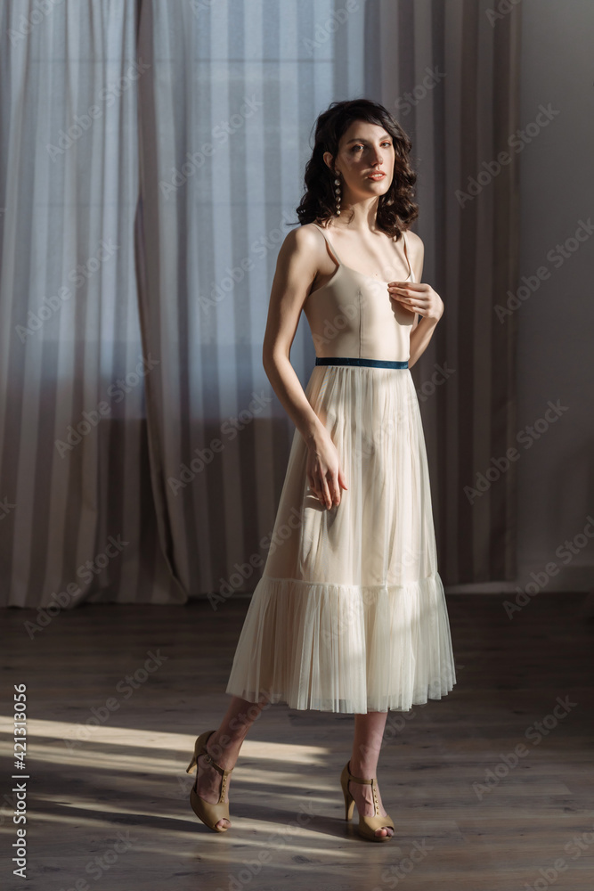 Cute young girl stands in the studio on the background of curtains. Stylish fashionable designer clothes. Cute young girl stands in the studio on the background of curtains. Stylish fashionable designer clothes.