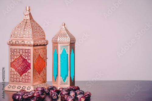 Ramadan concept. Dates close-up in the foreground. Ramadan Lantern on a wooden table. wall background. Space for text on the right. iftar concept image.