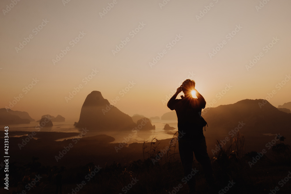 Young man taking picture of sun rise at Samed Nang Chee mountain view point, Phang Nga Province, Thailand. Young man taking picture of sun rise at Samed Nang Chee mountain view point, Phang Nga Province, Thailand.