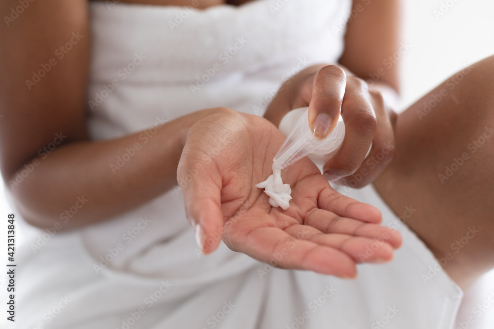 Mid section of woman using moisturizing cream in bathroom Mid section of woman using moisturizing cream in bathroom