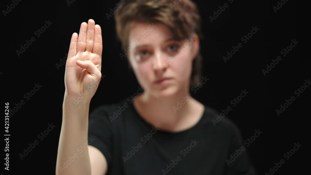 Close-up of female hand raising palm at camera with tuck thumb. Blurred ...