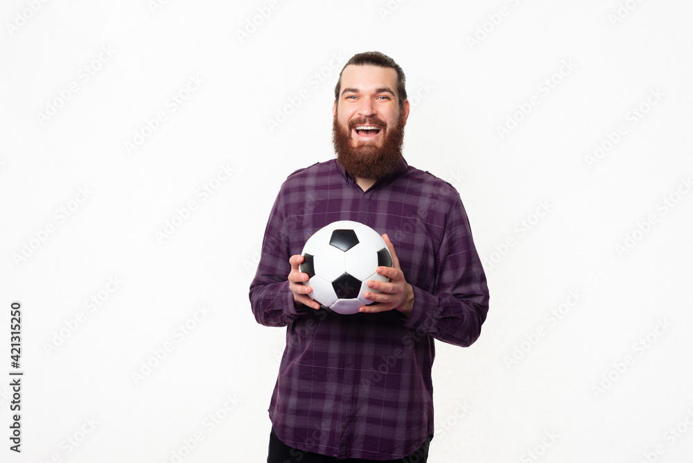 Photo of joyful bearded man in shirt holding soccer ball and supporting team