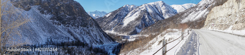 Panorama of Car Road along Valley of Sayan Mountains with Frozen Water Surface in Winter. Irkut River Covered with Ice and Snow