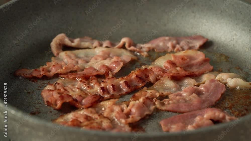 Keto meal fried fat bacon, ketogenic diet, british breakfast, thin slices of bacon sizzling in teflon frying pan, harmful cooking with carcinogens, crispy crust of food Keto meal fried fat bacon, ketogenic diet, british breakfast, thin slices of bacon sizzling in teflon frying pan, harmful cooking with carcinogens, crispy crust of food