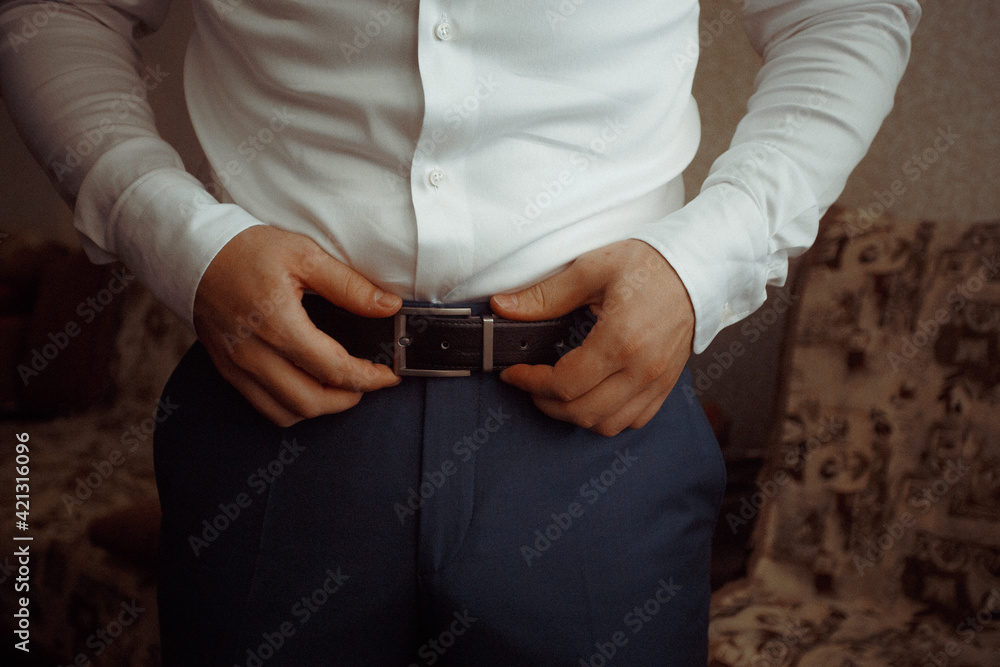 business man in shirt dresses and straightens leather belt close-up business man in shirt dresses and straightens leather belt close-up