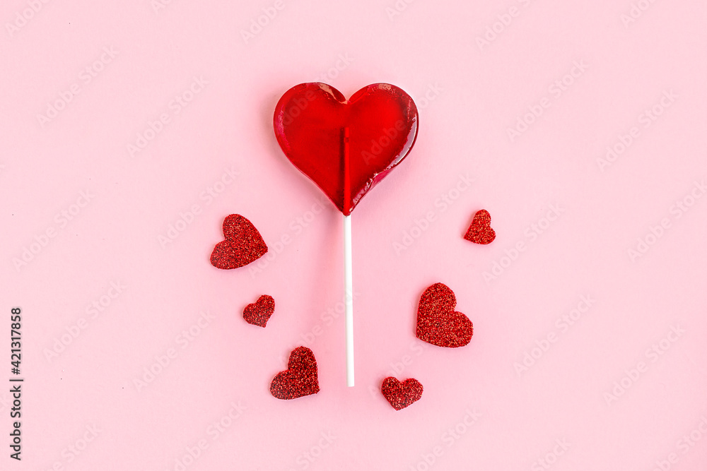 Red lollipop and hearts on pink background. Love and sweets concept. Flat lay, top view, copy space
