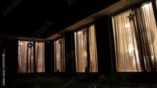 The light from windows of a house at night. View from outside.