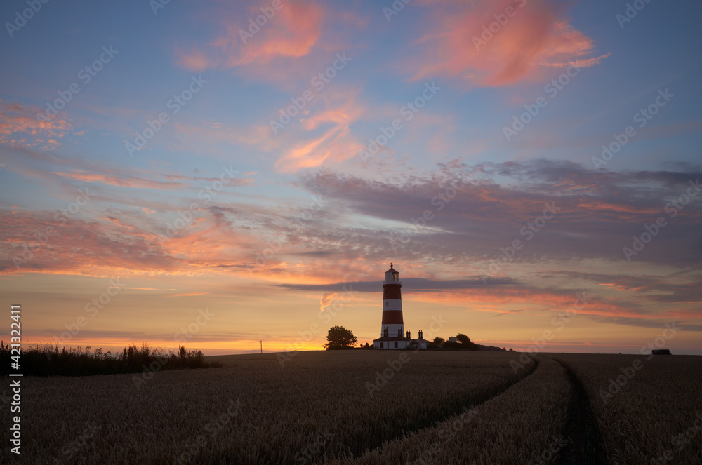 Dramatic sunset colour in the sky on the Norfolk coast at Happisburgh with the iconic lighthouse in the distance