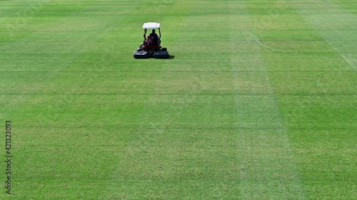 4k Footage: A staff on a lawn-mowing vehicle prepare a sports field on a sunny summer day in Dubai, United Arab Emirates photo