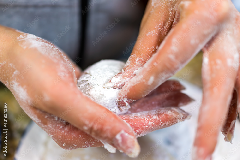Fototapeta premium Woman dirty hands holding, forming closing homemade mochi sticky glutinous Japanese rice cake dessert at home kitchen by plate
