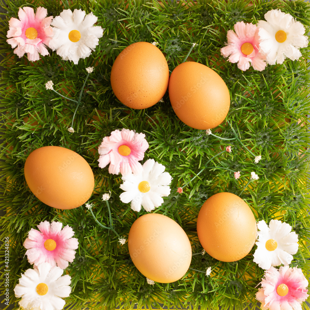 Easter concept made of grass and white and pink flowers as background and five natural eggs on top of it. Creative flay lay. Easter concept made of grass and white and pink flowers as background and five natural eggs on top of it. Creative flay lay.