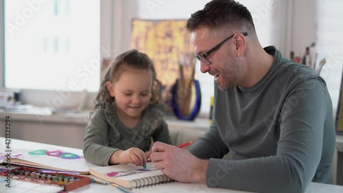 Caring caucasian dad babysitter drawing with colored pencils teaching child girl sitting at the table, father enjoy helping kid daughter playing doing homework at home, happy family creative activity