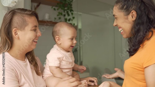 lesbian mother playing with peekaboo with baby in the kitchen
