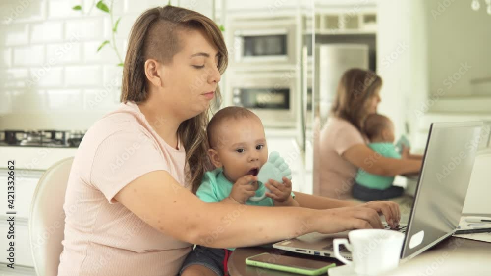 young mother typing and working in laptop with infant child in the kitchen
young mother typing and working in laptop with infant child in the kitchen