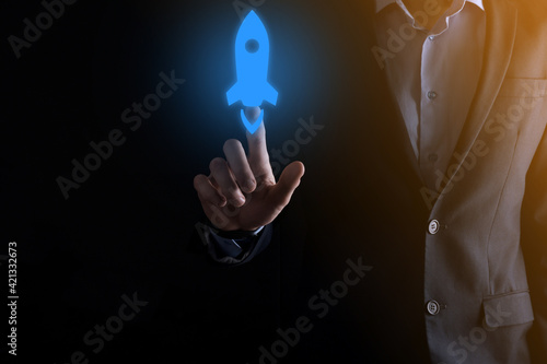 Startup business concept, Businessman holding tablet and icon rocket is launching and soar flying out from screen with network connection on dark background.