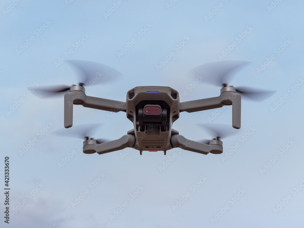 Grey drone with camera flying in the air outdoors. Little drone flying outside in sky. Grey drone with camera flying in the air outdoors. Little drone flying outside in sky.