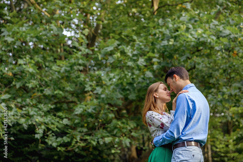 beautiful loving couple in the park look at each other hug on the background of green trees © Ivan