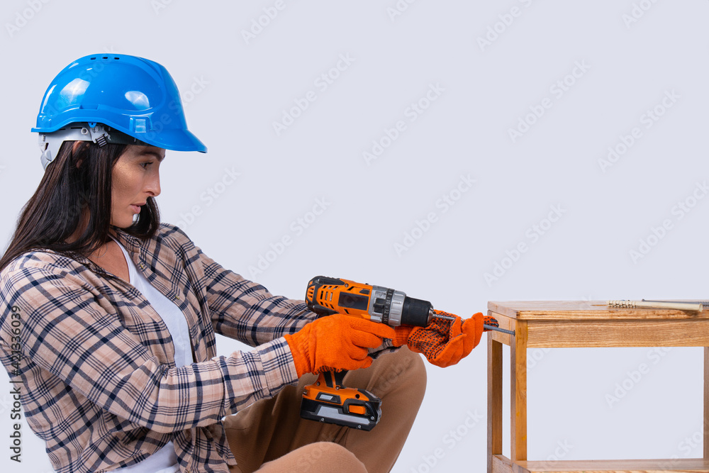 Female carpenter drills a hole with an electrical drill. Repair and renovation concept. Woman repair tools for house constructor. Cordless drill, screwdriver with drills
