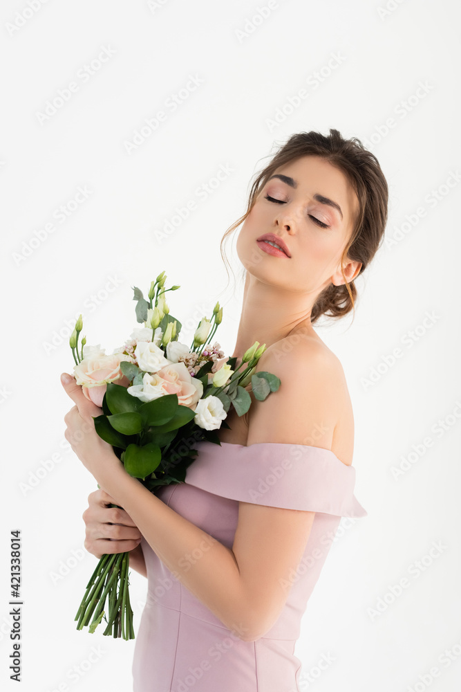 charming woman holding wedding bouquet while standing with closed eyes isolated on white