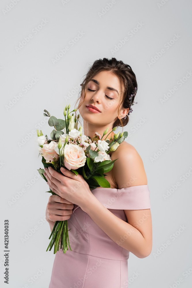 charming bride holding wedding bouquet while standing with closed eyes isolated on grey charming bride holding wedding bouquet while standing with closed eyes isolated on grey