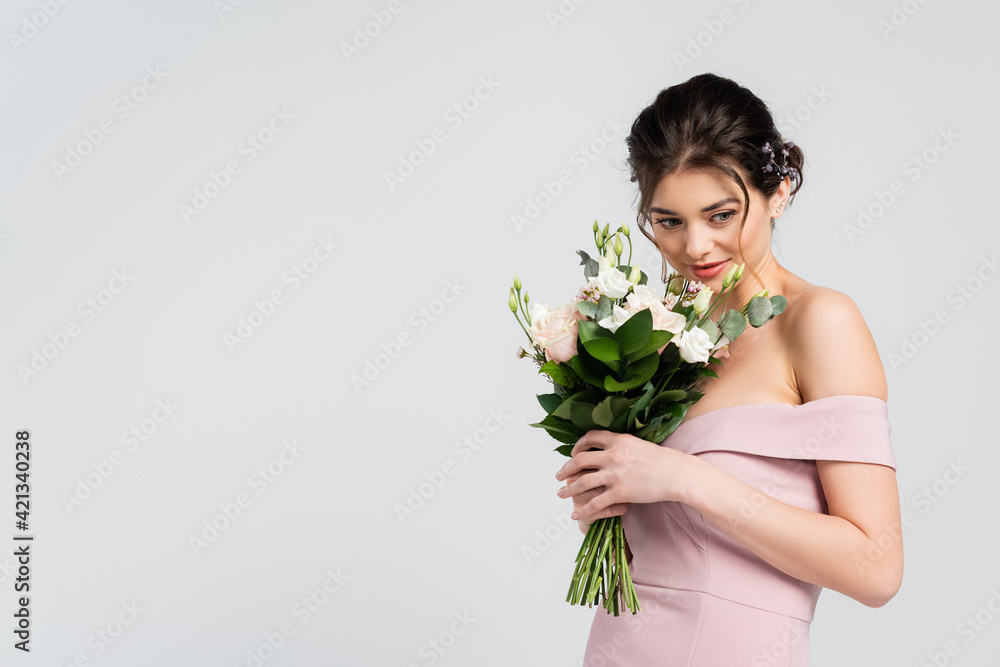 sensual woman in elegant, pink dress holding wedding bouquet isolated on grey