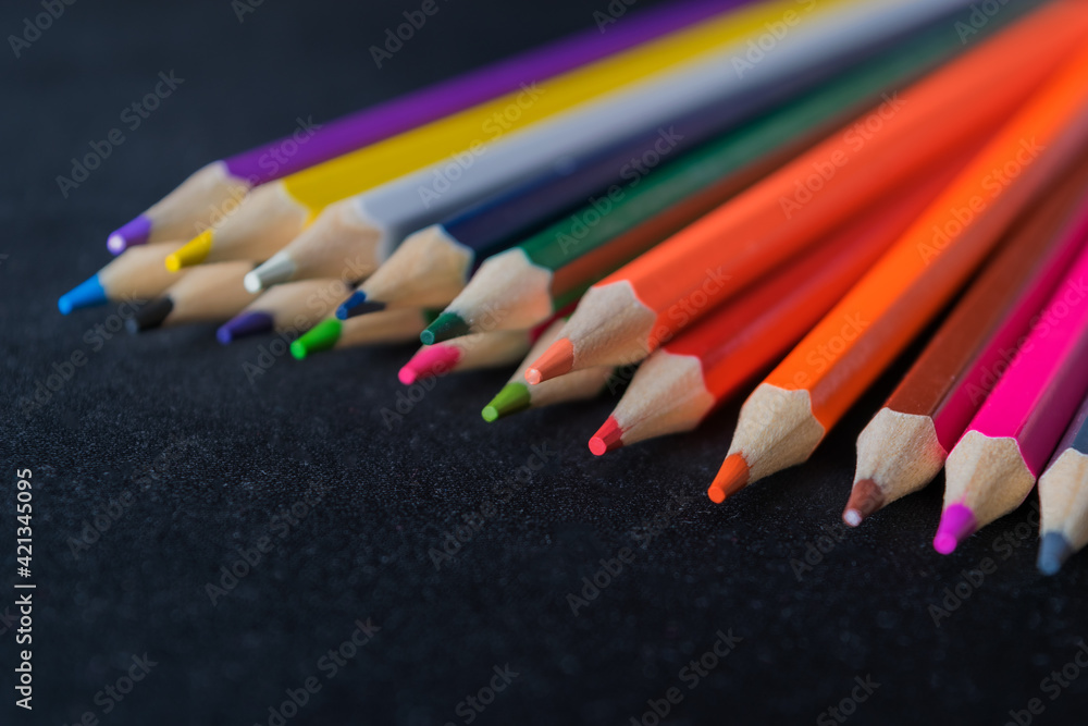 Colored pencils on a dark background. Defocus. Close-up. Colored pencils on a dark background. Defocus. Close-up.