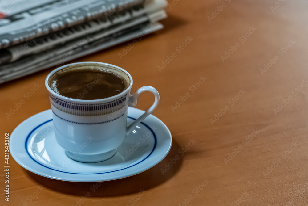 Obraz premium A cup of Turkish coffee and old newspaper on the wooden table.