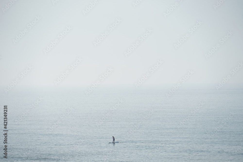 stand up paddler on ocean on foggy day