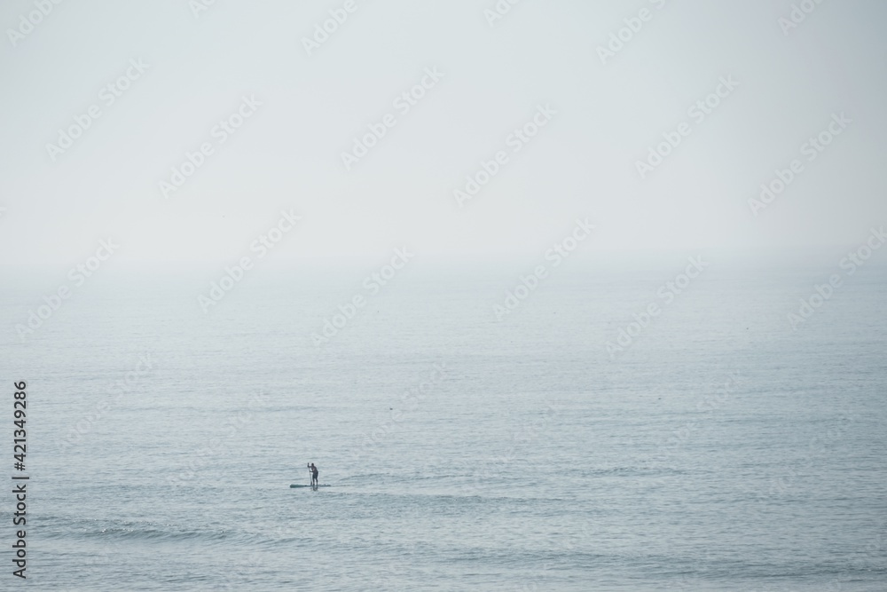 stand up paddler on ocean on foggy day