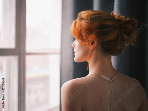 Portrait of a redhead woman near the window