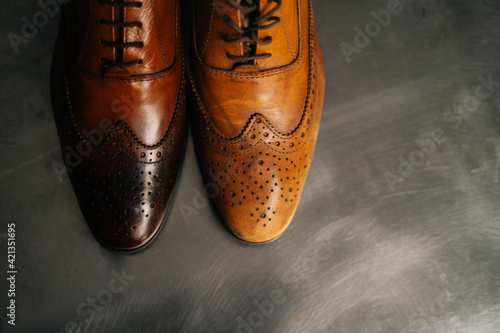 Close-up top view of old light brown leather shoe and repaired shiny shoes after restoration working. Concept of cobbler artisan repairing and restoration work in shoe repair shop.