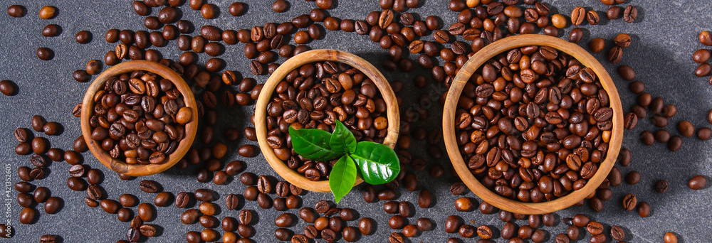 Roasted brown coffee beans on a gray background. Coffee beans in wooden bowls. Top view.