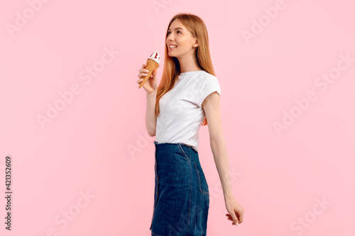 young woman  in a summer hat  with a huge ice cream cone on a pink background