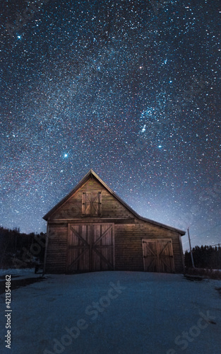 Old farm barn with a sky filled with stars on a cold winter night. © Josh