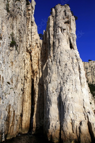 Close-up view of the steep rock walls of the creek with climbers in action, Parc National des Calanques, Marseille, France