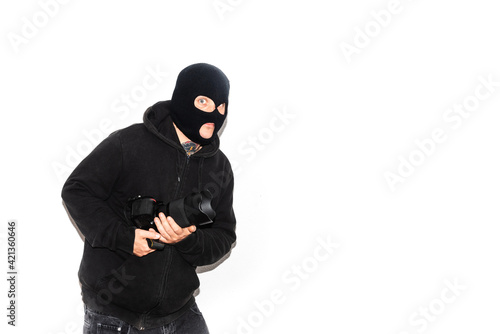 thief with balaclava and tattoos on white background. Person stealing photo camera. Crime and delinquency. Home security and insurance.