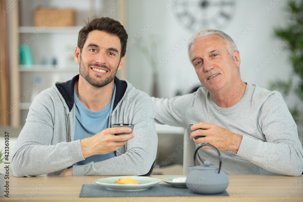 son and father taking tea at home son and father taking tea at home