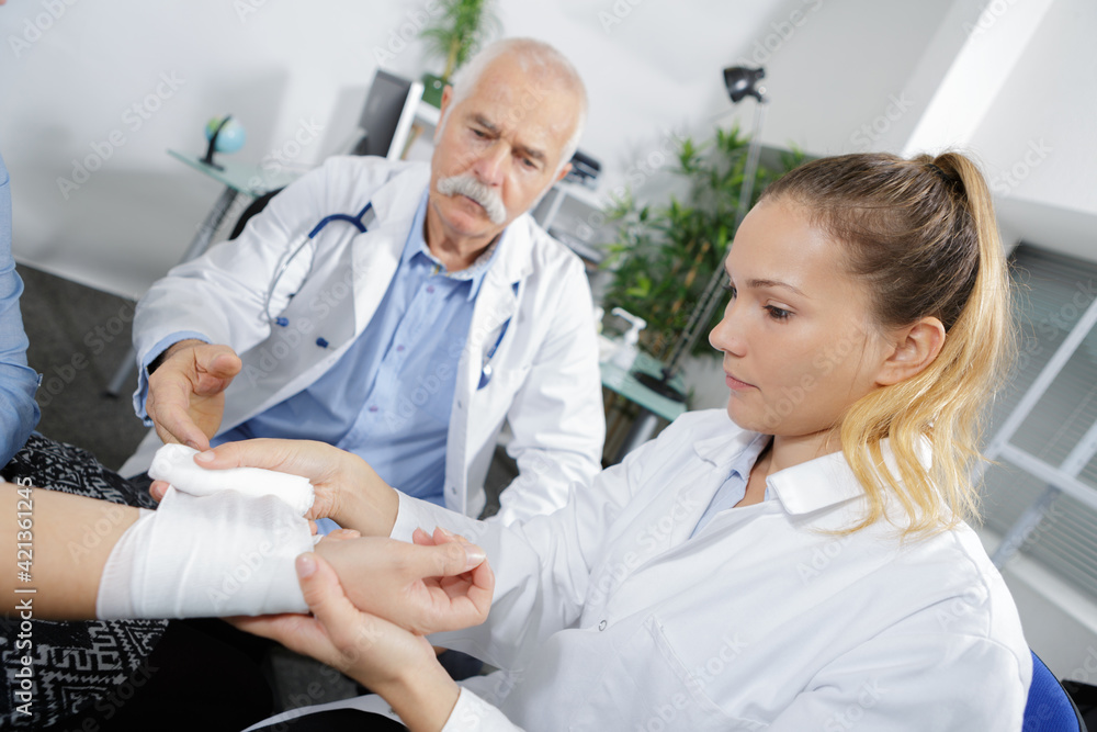 nurse being supervised to bandage patients wrist nurse being supervised to bandage patients wrist