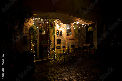 Fototapeta Naklejka Na Ścianę i Meble -  Cafe lights on a rainy night in Trastevere, Rome Italy