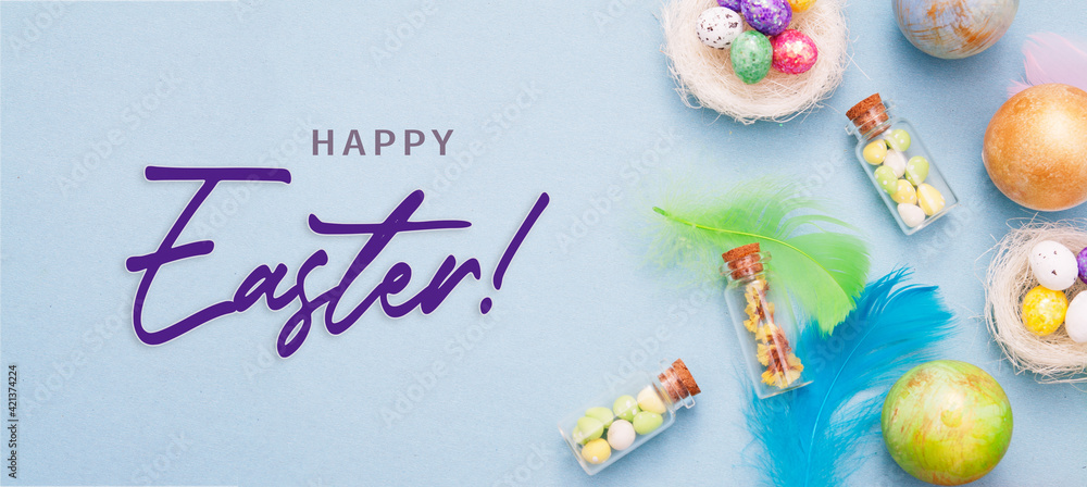 Happy Easter banner with decorative eggs in nest and glass bottles with color feathers on a blue background Happy Easter banner with decorative eggs in nest and glass bottles with color feathers on a blue background