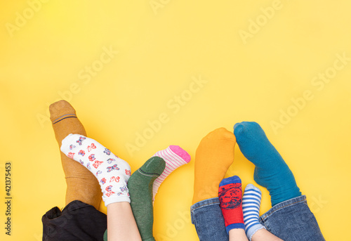 International Day of people with Down Syndrome, 21st of march. Feet of a little boy with Down Syndrome, his sister, mother and father on a bright yellow background with socks of different colors.  photo