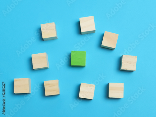 Dissenting opinion, stand out and different concepts. Selective focus wooden cubes with one green color isolated on blue background.