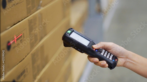 Close up hand scanning products with barcode scanner in warehouse.