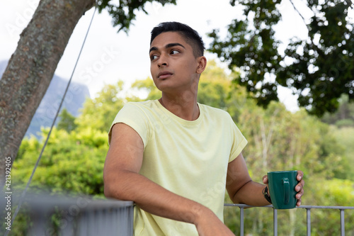 Mixed race man holding cup of coffee on balcony