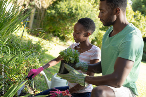 African american couple gardening and smiling on sunny garden terrace