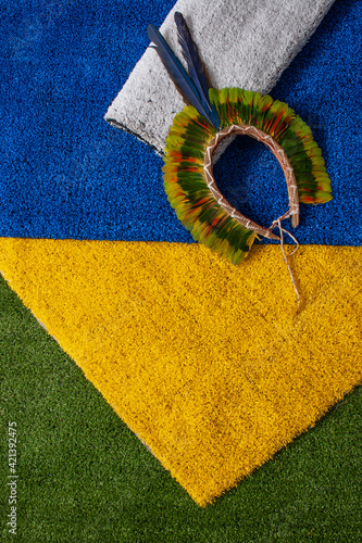 Indian headdress and top of rugs in the colors of the Brazilian flag